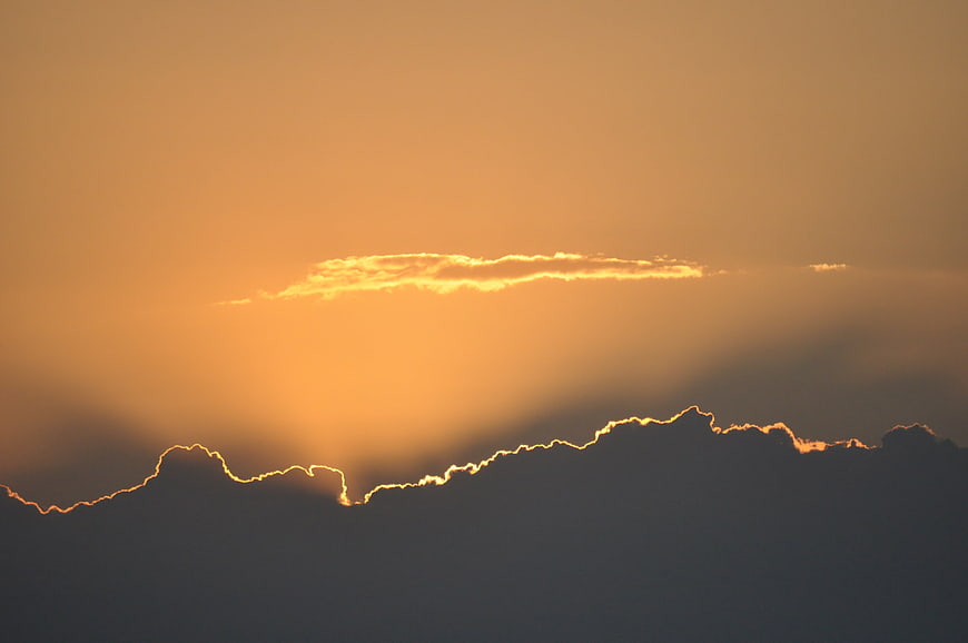 Golden sunset sky with dramatic cloud silhouette and sun rays