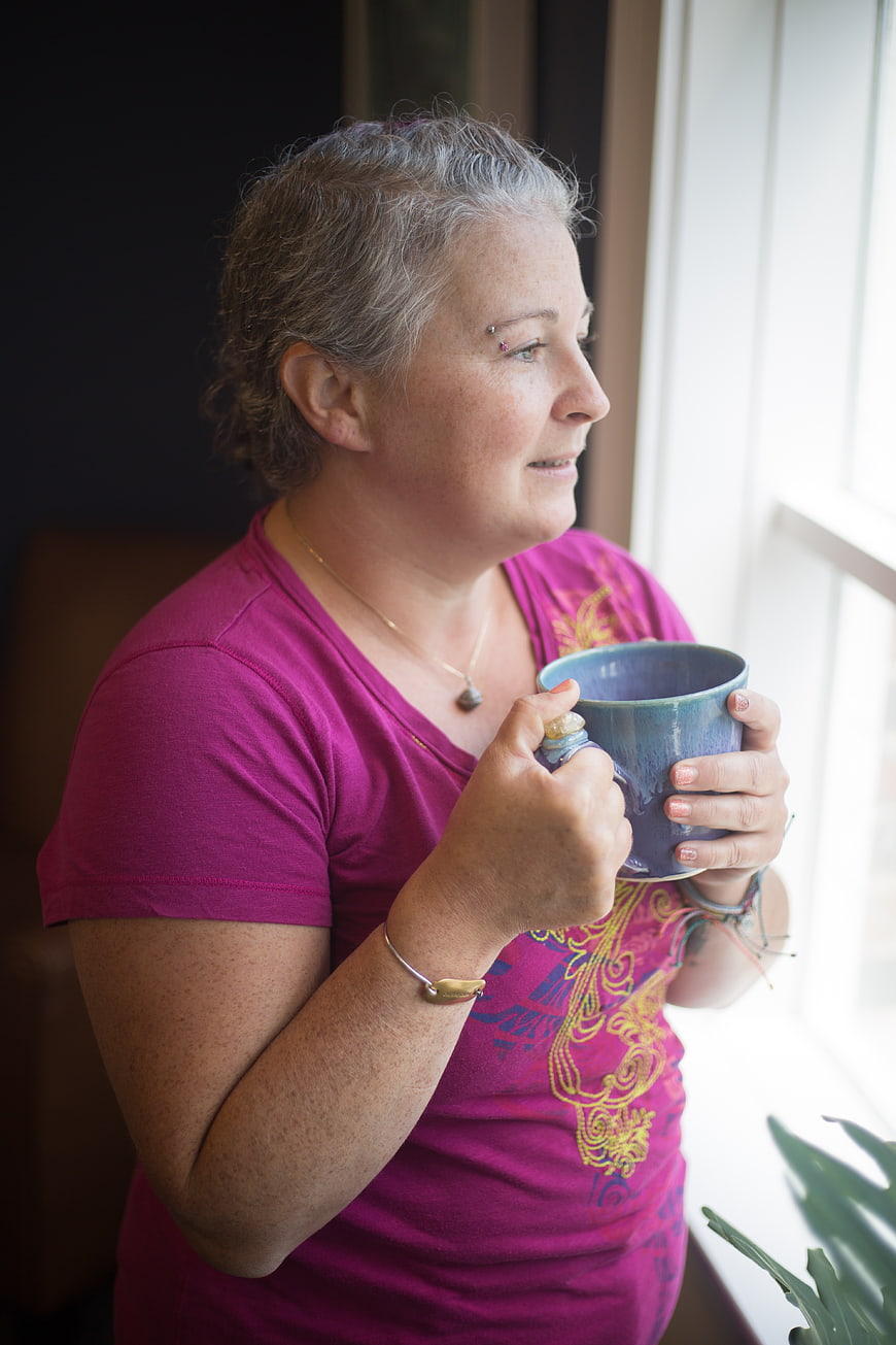 Senior Woman Holding Blue Mug by Window