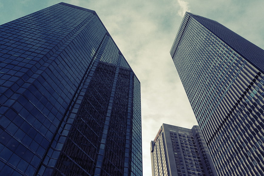 Low angle view of modern glass skyscrapers against a cloudy sky