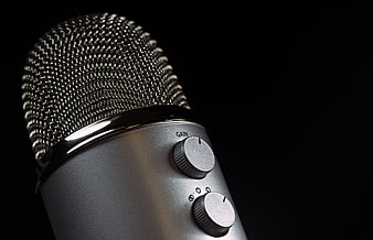 Close-up of silver studio microphone with gain knob on black background