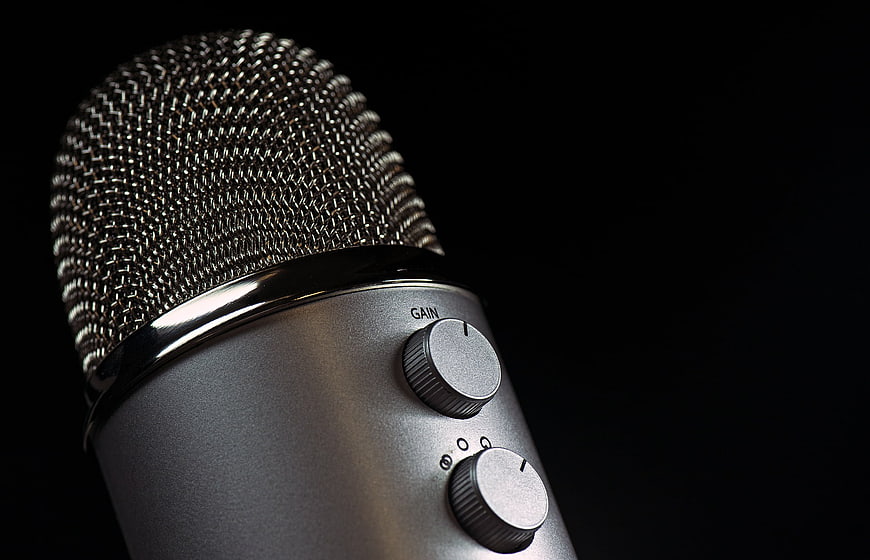 Close-up of silver studio microphone with gain knob on black background