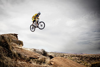 Mountain biker jumping over rocky desert cliff
