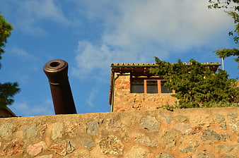 Historic Cannon on Stone Wall Against Blue Sky