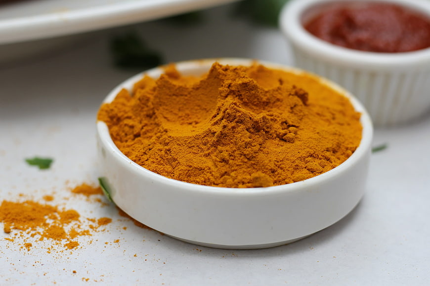 Close-up of vibrant turmeric powder in a white bowl