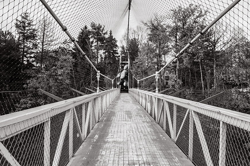 Black and white view of suspension bridge with giant hand sculpture