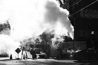 Black and white street scene with steam rising from manhole