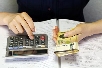 Person Calculating Korean Won Banknotes With Calculator