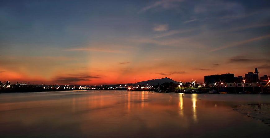 Panoramic Sunset Over Harbor With City Lights and Mountain