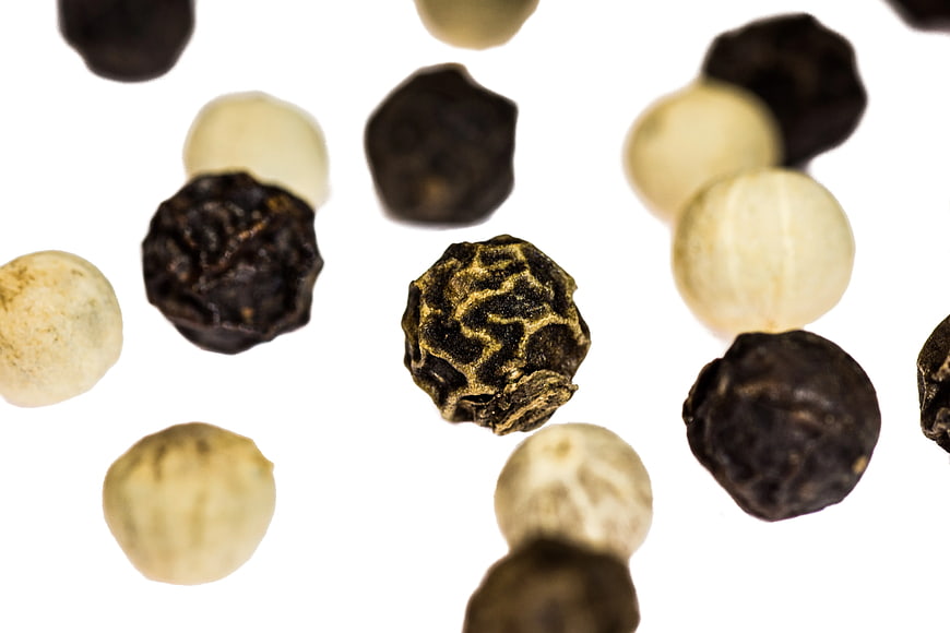 Black and white peppercorns on white background