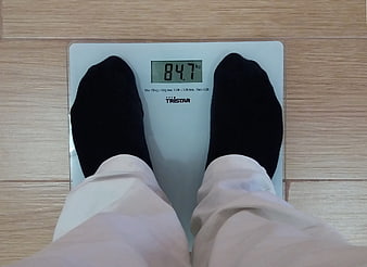 First-person view of feet in black socks on a digital bathroom scale