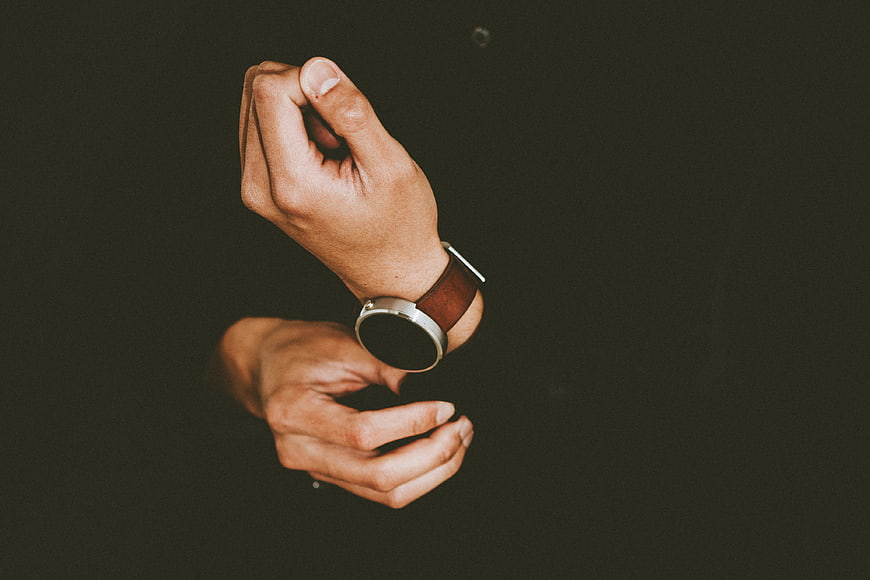 Man checking smartwatch on wrist against dark background