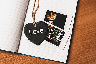 Heart-shaped chalkboard with 'Love' on notebook with polaroids