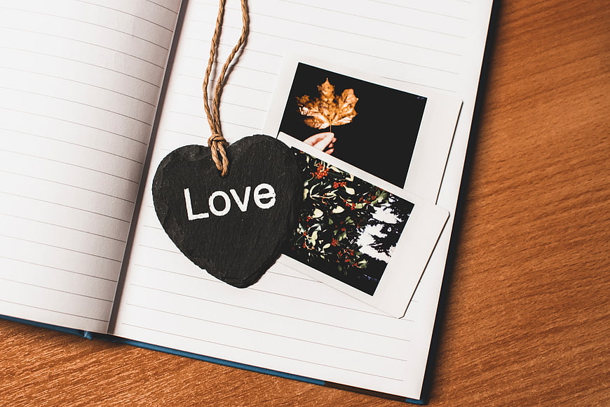Heart-shaped chalkboard with 'Love' on notebook with polaroids