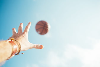 Hand Catching Basketball Against Blue Sky