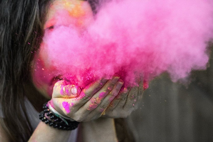 Woman Throwing Vibrant Pink Powder in Air