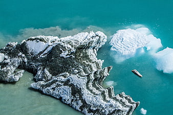 Aerial view of boat near icebergs and rocky coast
