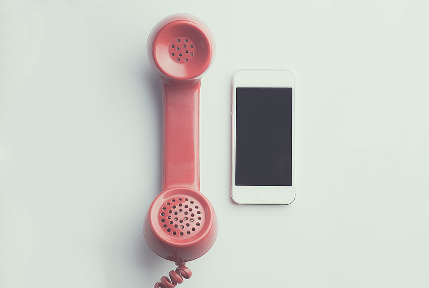Vintage pink telephone handset and modern smartphone on white background