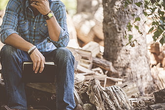 Man in Plaid Shirt Sitting in Woods with Notebook