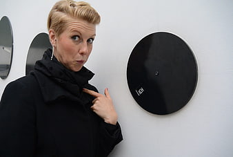 Woman pointing at black circular art installation on white wall