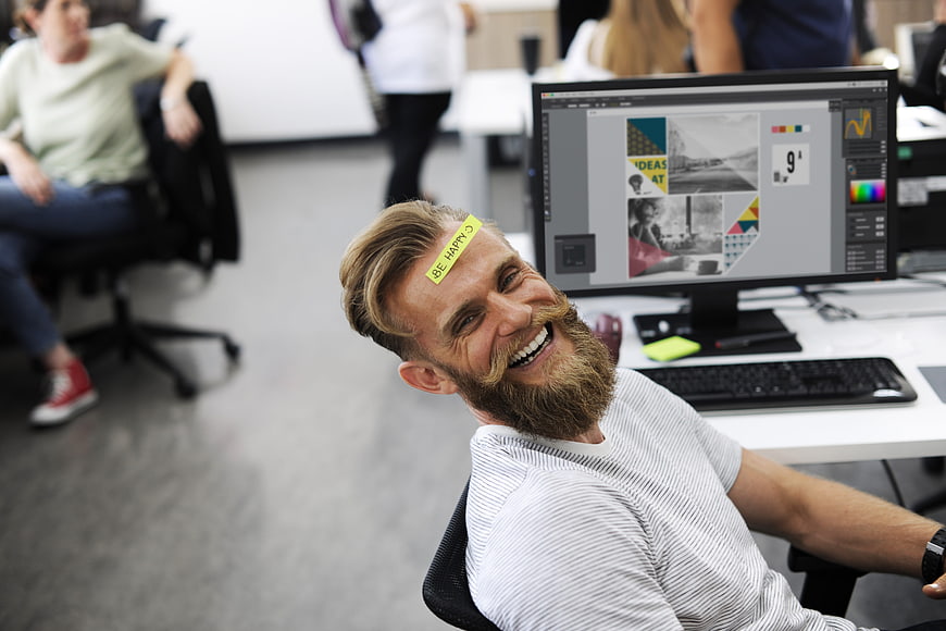 Happy bearded man with sticky note on forehead in office