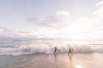 Couple Running on Beach at Sunset with Waves