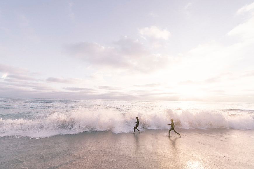 Couple Running on Beach at Sunset with Waves