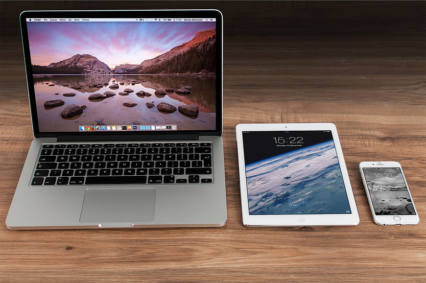 MacBook, iPad, and iPhone on wooden desk workspace