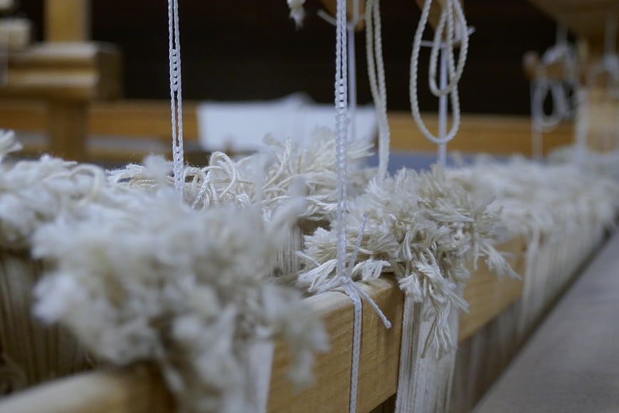 Close-up of white yarn on a wooden weaving loom