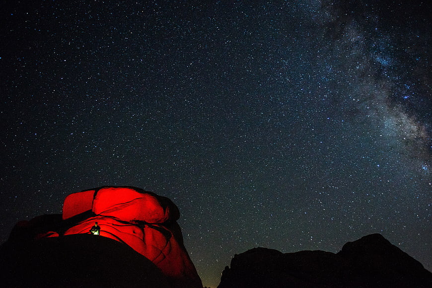 Red illuminated rock formation under Milky Way night sky