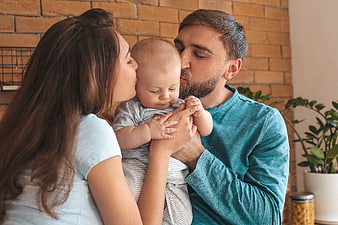 Young Parents Kissing Baby at Home