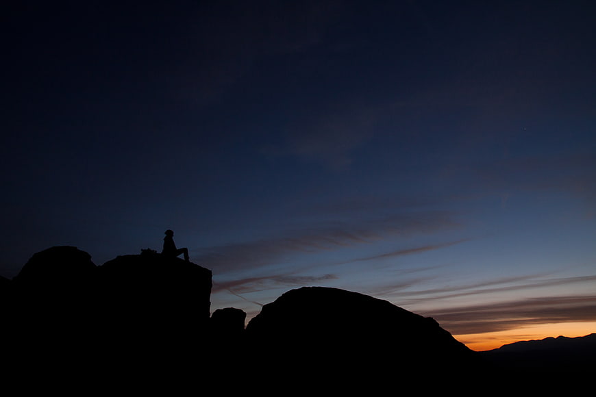Silhouette of Hiker Sitting on Mountain Peak at Sunset