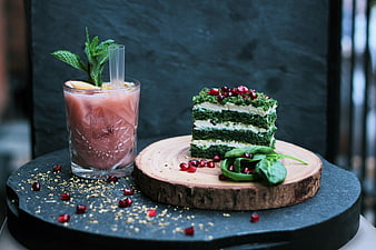 Green layered cake slice and pink smoothie on slate board
