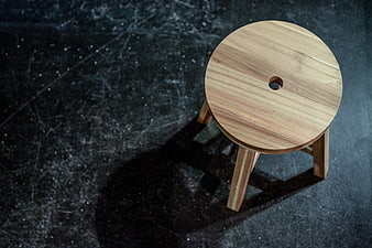 Minimalist wooden stool on dark textured background