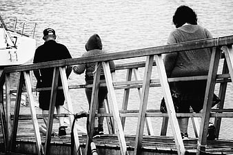 Three people standing on wooden pier looking at water