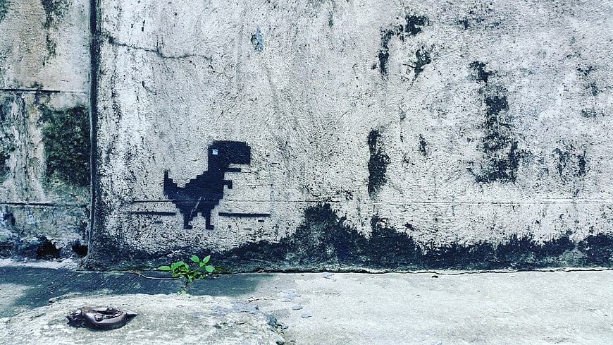 Pixelated Dinosaur Street Art on Weathered Concrete Wall