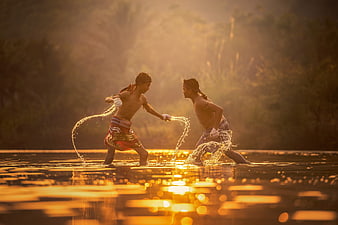 Two Boys Boxing in Water at Golden Sunset