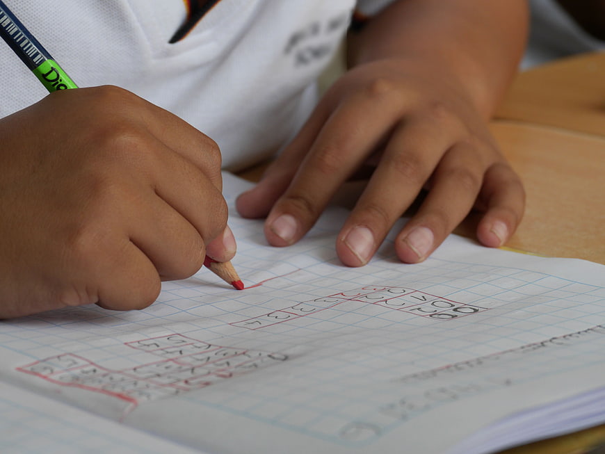 Child Writing Numbers in Notebook with Pencil