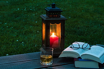 Relaxing evening reading setup with lantern, whiskey, and books