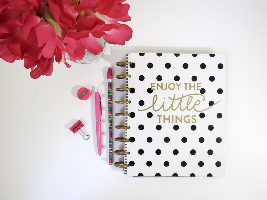 Flat lay of polka dot notebook with pink flowers and stationery