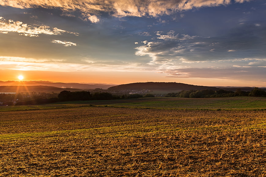 Golden Sunset Over Rural Farmland and Rolling Hills