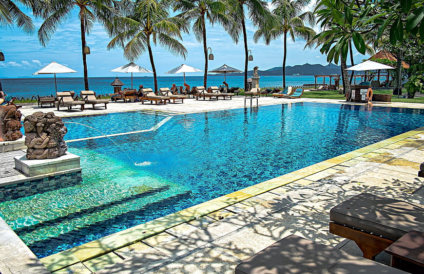 Luxury tropical resort pool with ocean view and palm trees