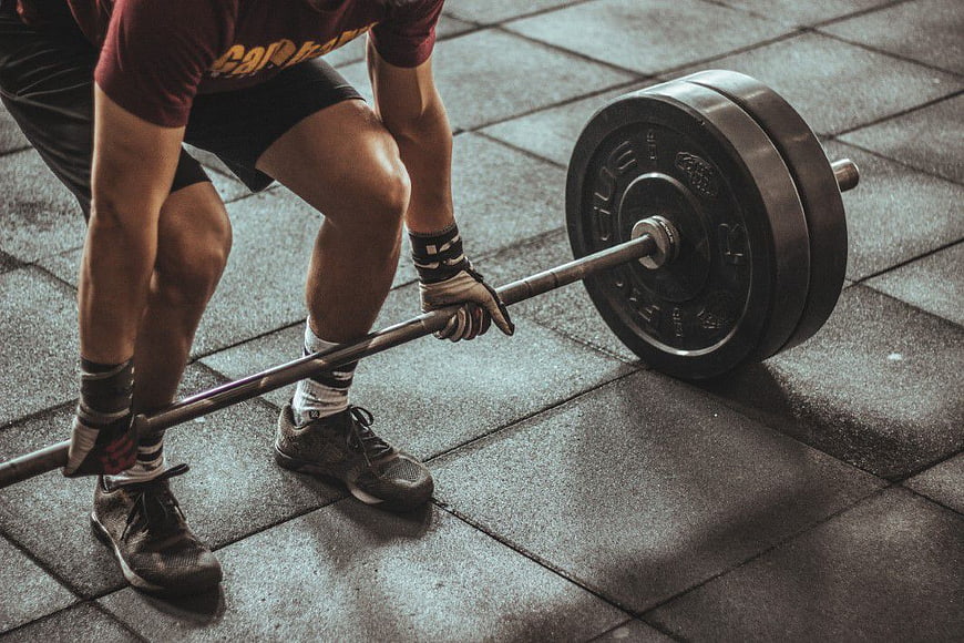 Athletic Man Lifting Barbell in Gym