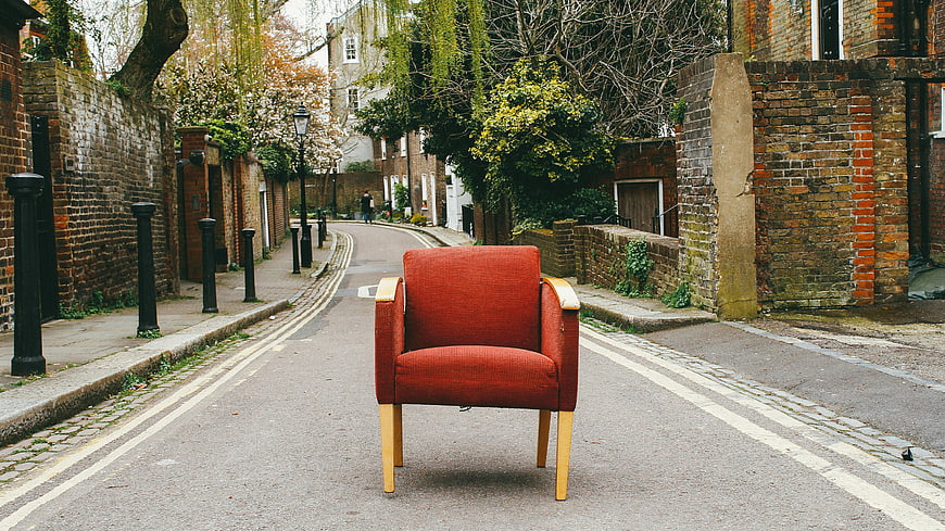 Red armchair sitting alone on a quiet residential street