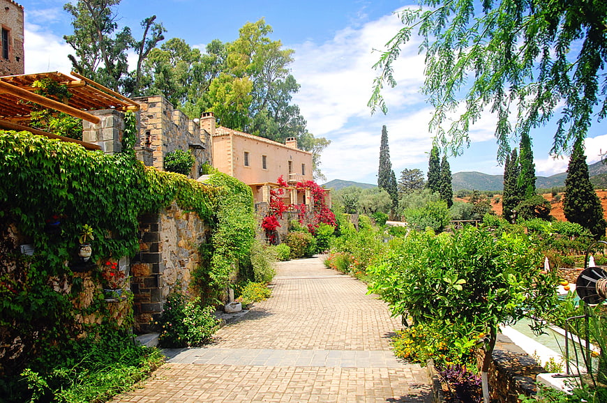 Lush Mediterranean Garden Pathway with Stone Villa and Cypress Trees