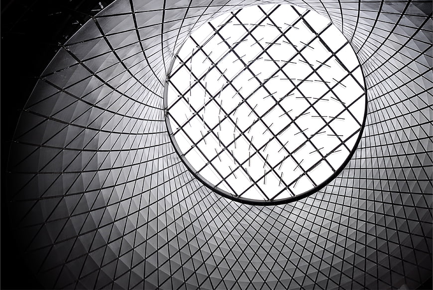 Black and white modern architecture looking up at circular glass skylight