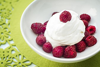 Fresh Raspberries And Whipped Cream In White Bowl On Green Background