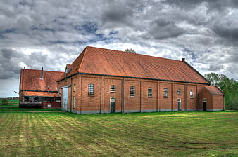 Old red brick industrial building under dramatic cloudy sky