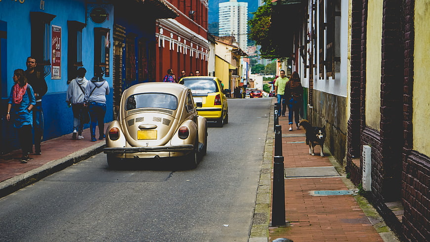 Gold Volkswagen Beetle on Colorful Street with Pedestrians