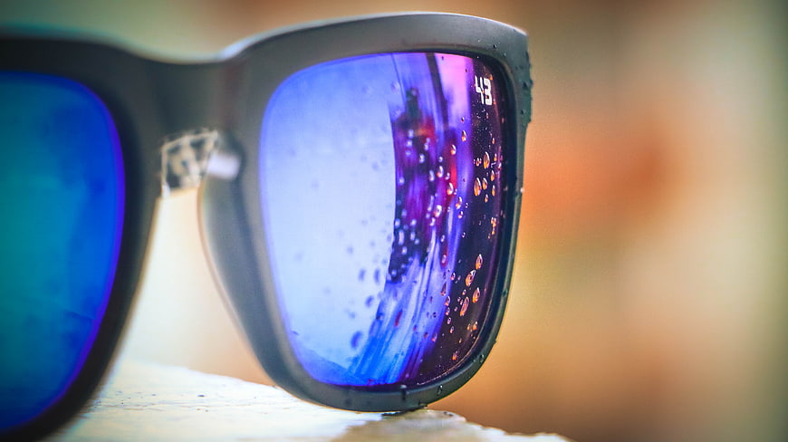 Close-up of sunglasses with water droplets on blue reflective lenses