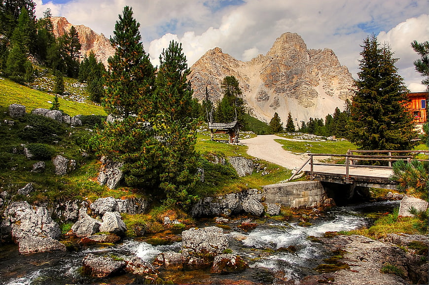 Alpine stream with wooden bridge and mountain peaks